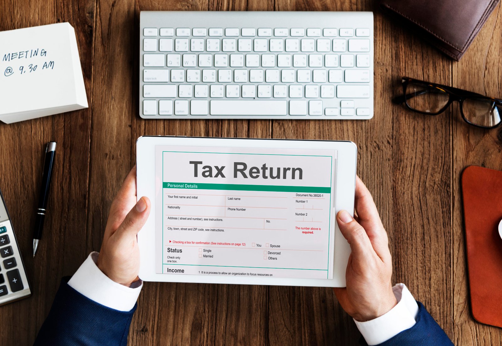 Hands holding a tablet showing a tax return form
